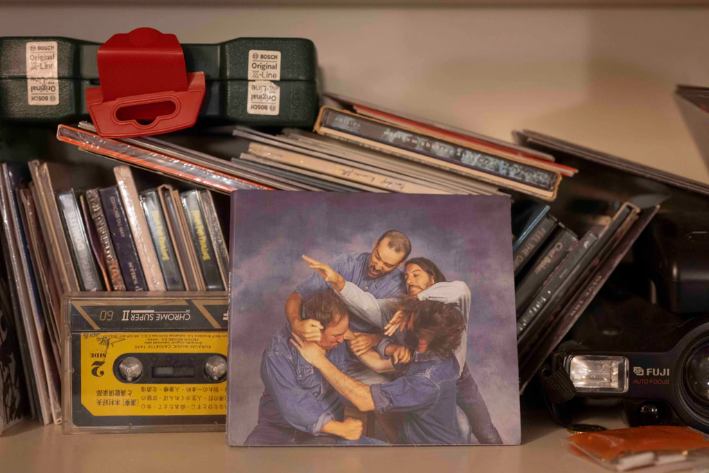 Pochette de l'album « Top Of The Line » des Swirls, posée contre une pile de vinyles et de CD, avec une cassette et un vieil appareil photo Fuji